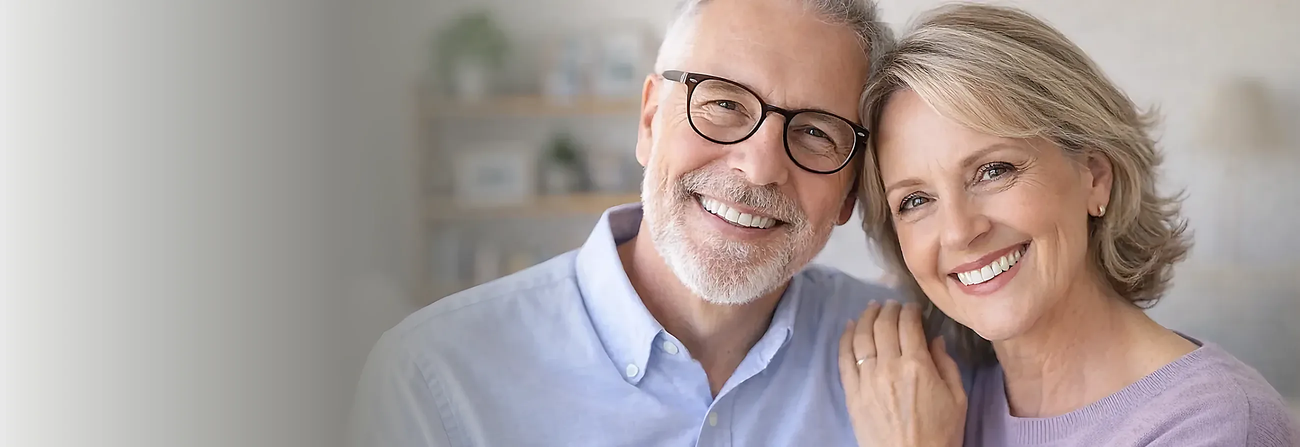 An older couple smiling together after being fitted with dentures