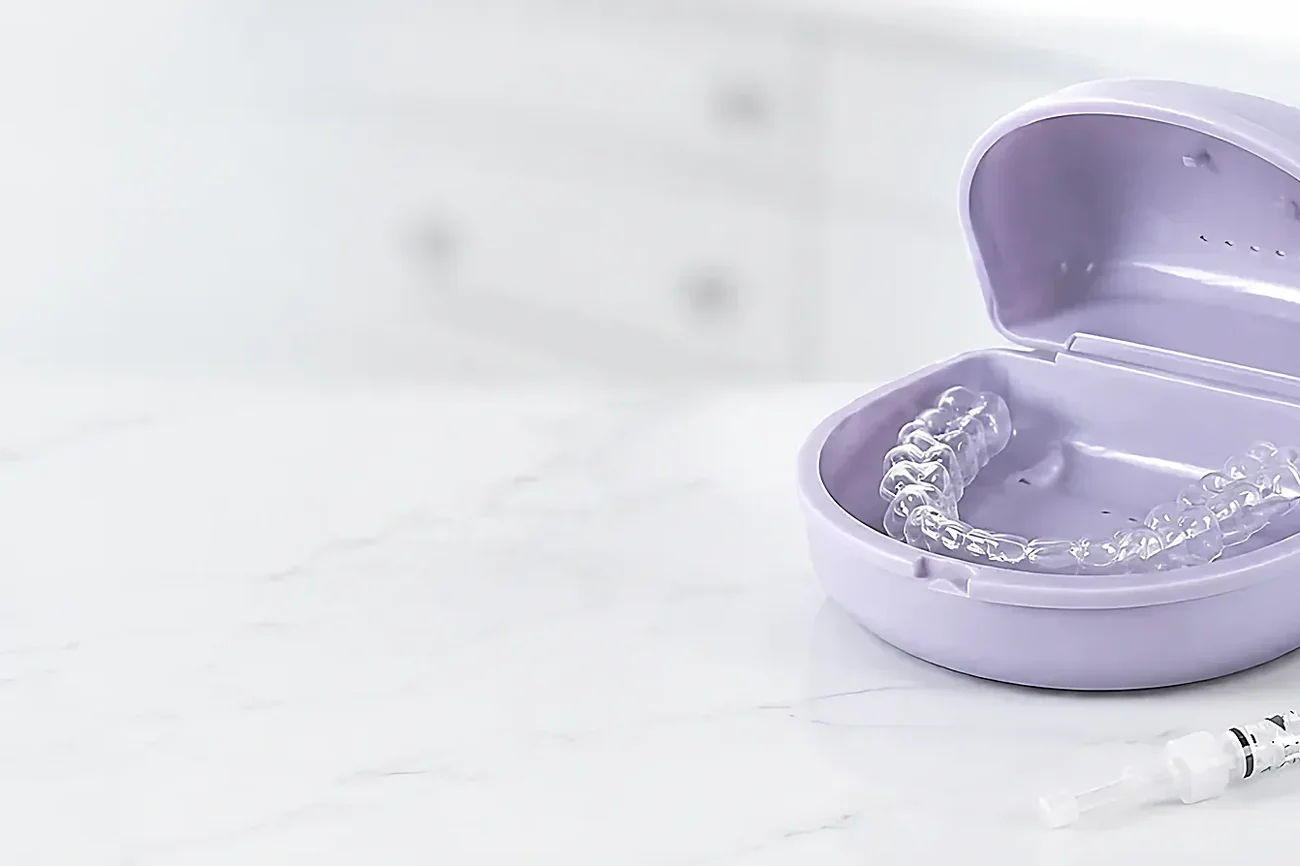 A take-home whitening tray in its case beside a gel syringe