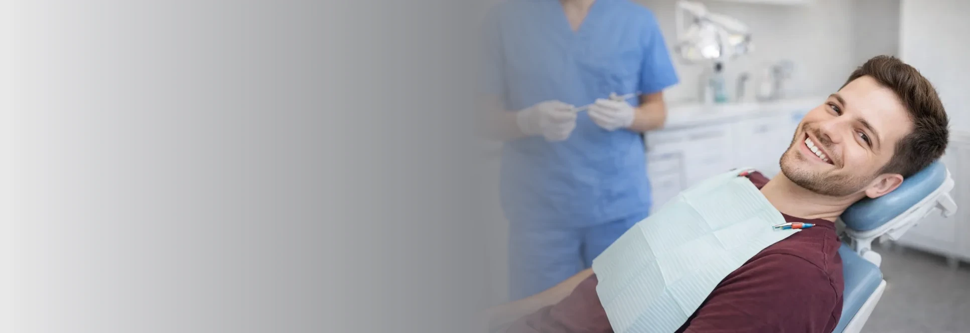 A smiling patient in the dental chair with a hygienist behind him