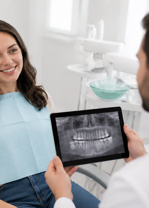 A dentist showing a smiling patient her X-ray on a tablet